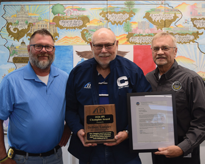 Delbert Longley holding his award standing in between Clint Schmidt and Bob Fairfax